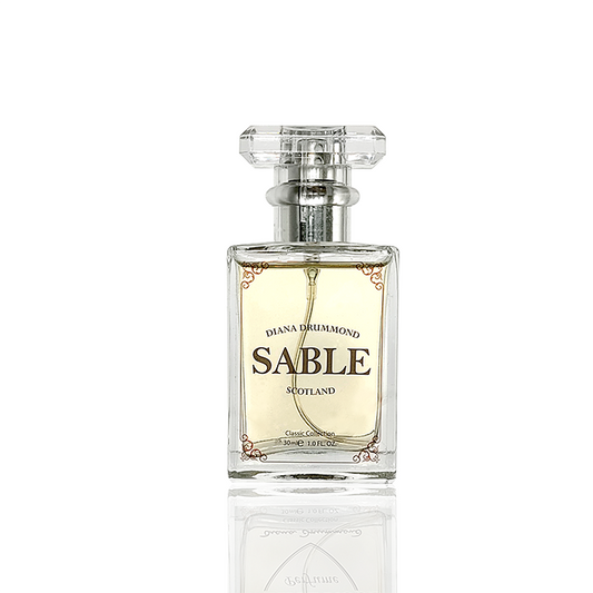 Sable perfume resting beside a wool tartan scarf, inspired by the Scottish Highlands