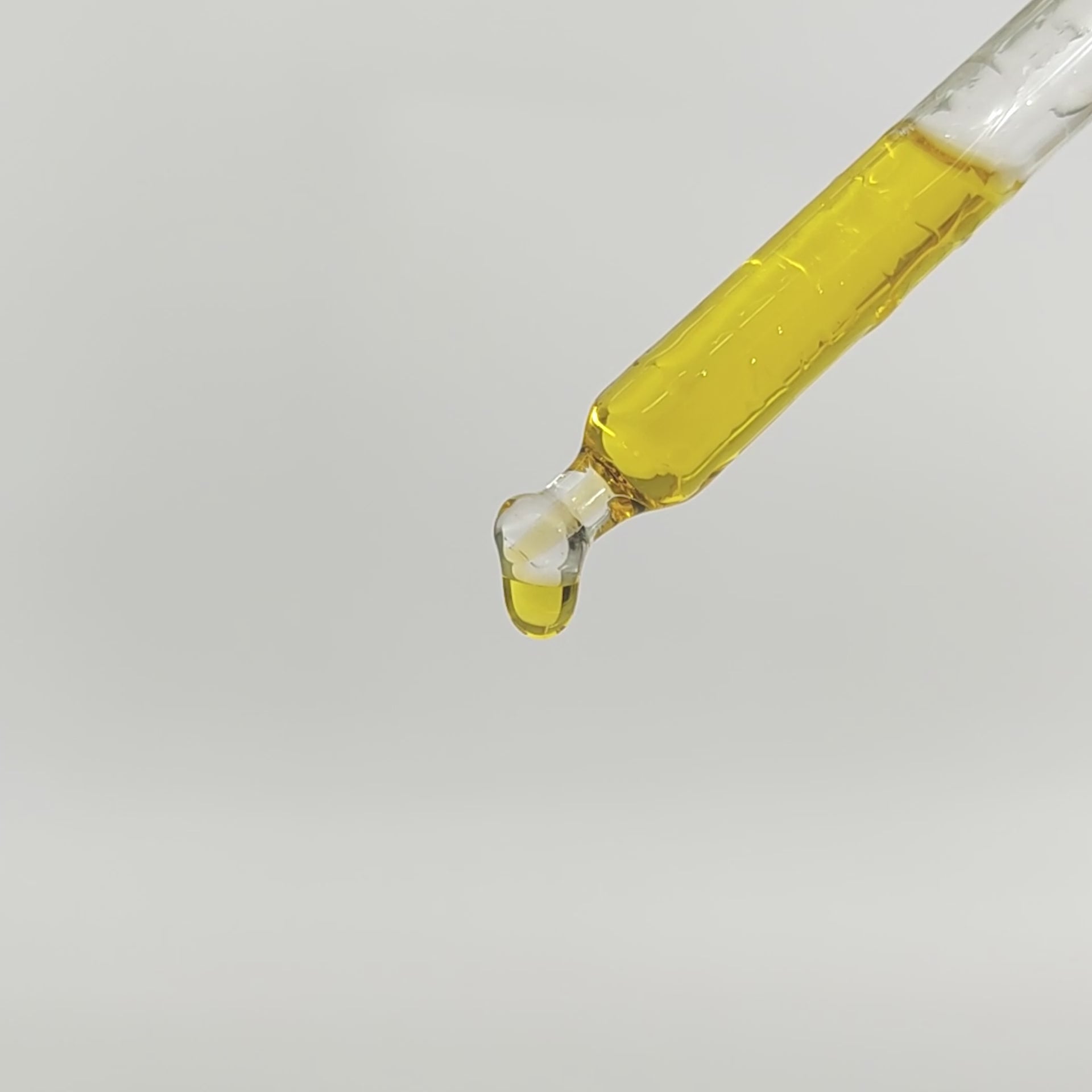 Dropper of facial oil mid-application over soft light background with marine botanicals